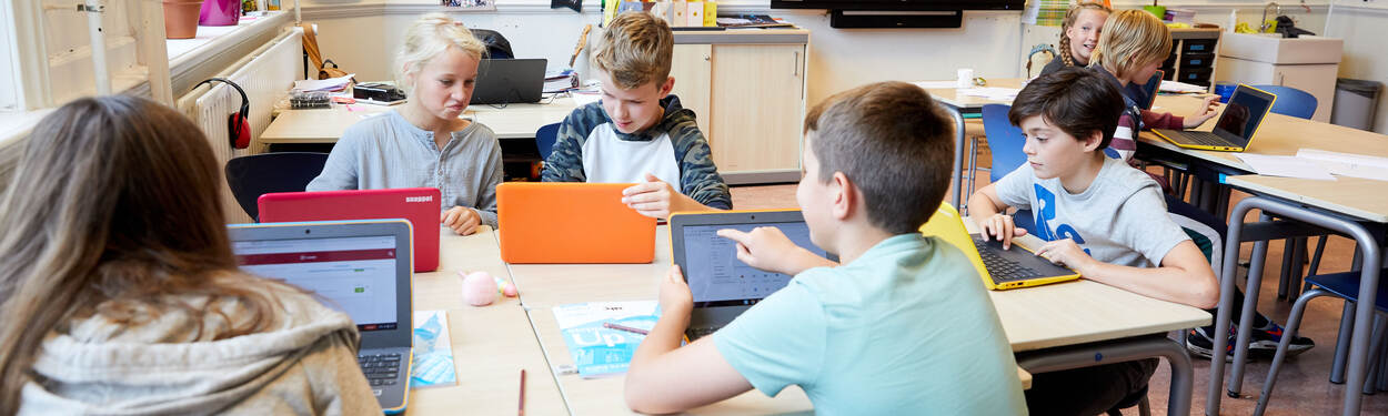 5 leerlingen in een groepje werken individueel aan een opdracht op de laptop