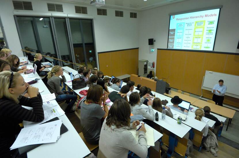 Leraar geeft les in collegezaal.