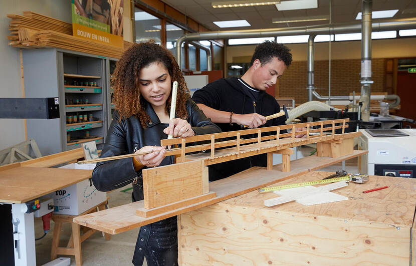 Twee mbo studenten aan het werk met hout in een werkplaats