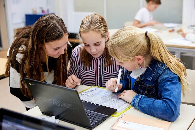 3 meisjes in de klas achter een laptop, bezig met een opdracht