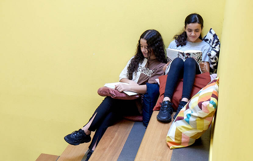 2 meiden uit groep 8 lezen op een speelse manier op een schooltrap