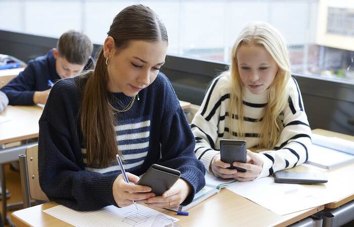2 meisjes in de klas aan het werk aan rekensommen met een rekenmachine