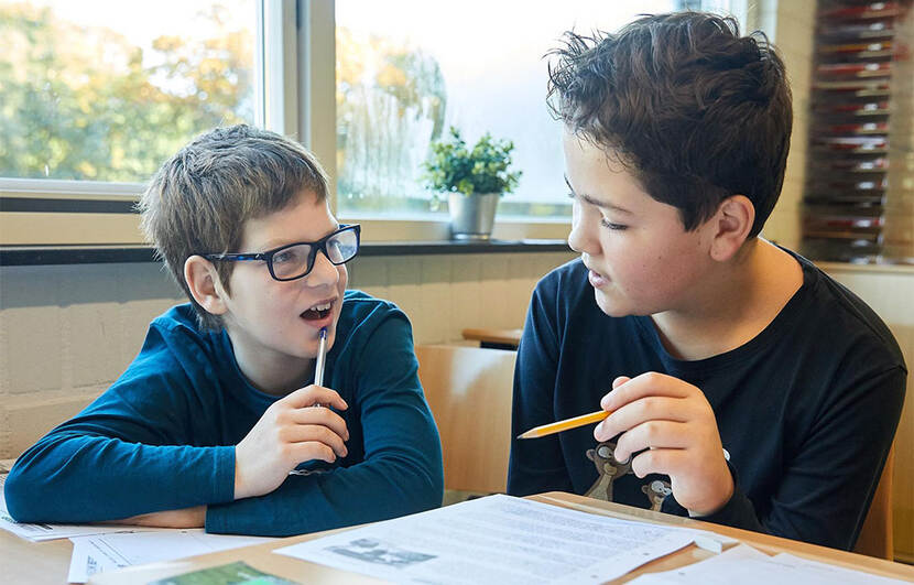 Twee jongens bespreken een opdracht in de klas